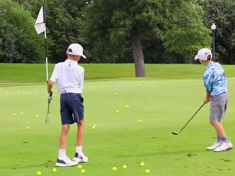 Juniors line up putts on the practice green in front of the clubhouse