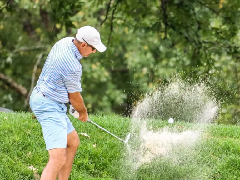 A member plays out of the rough under the oaks on the Elgin course