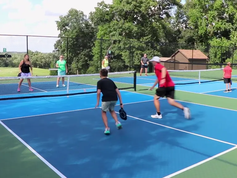 Members mid-rally on the blue pickleball courts